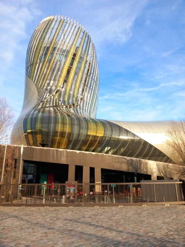 un bâtiment avec un toit incurvé, des tables et des chaises dans l'établissement Bateau au bassin des lumières, à Bordeaux