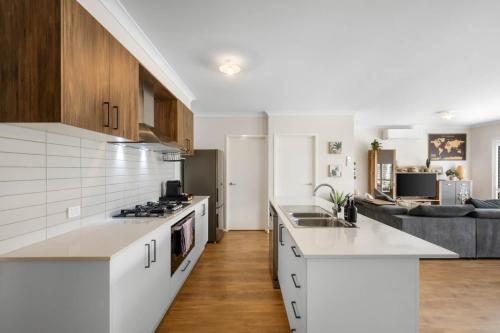 a kitchen with white cabinets and a living room at Rowands Residence Mt Duneed in Mount Duneed