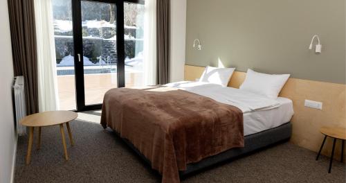 a bedroom with a bed and two tables and a window at Dilijani Tun Hotel & Restaurant in Dilijan