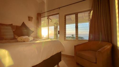 a bedroom with a bed and a chair and a window at 4 Chaka's Rocks Chalets - The Beach Cottage in Ballito