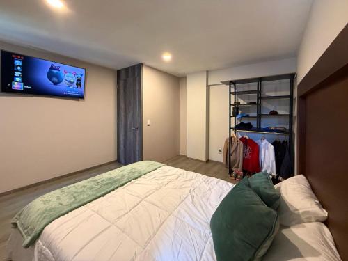 a bedroom with a bed and a tv on the wall at FIKA Apartamentos Elite in Toluca