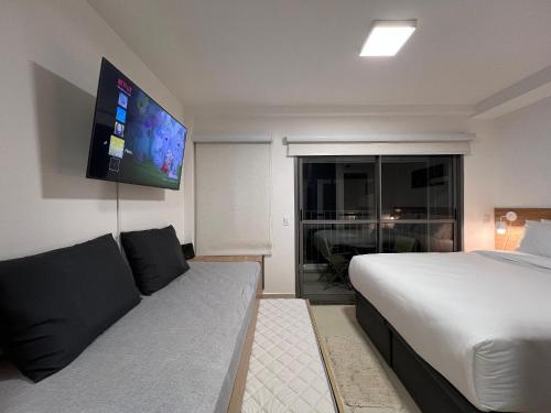 a bedroom with a bed and a tv on the wall at Lindos Studios na Liberdade AC/WF/Proximo ao Metro in Sao Paulo