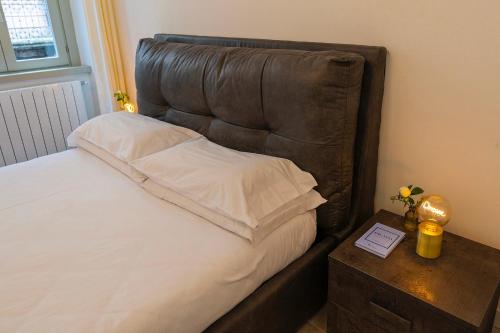 a bed with a leather headboard next to a night stand at Magic Place Bergamo! Classy Apartment in the heart of the city in Bergamo