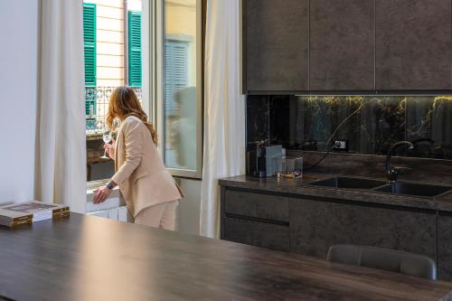 a woman standing in a kitchen looking out the window at Magic Place Bergamo! Classy Apartment in the heart of the city in Bergamo