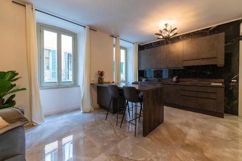 a kitchen with a bar with black stools in it at Magic Place Bergamo! Classy Apartment in the heart of the city in Bergamo