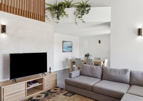 a living room with a couch and a flat screen tv at Mariners Rest - Heated pool and outdoor spa in Yamba