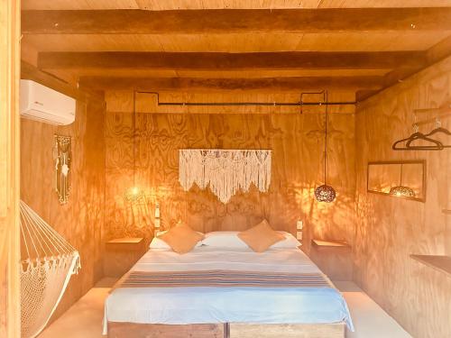 a bedroom with a bed in a wooden wall at Hotel Cabañas y Glamping Punta Surf in Brisas de Zicatela