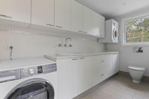 a white kitchen with a washing machine in it at Casa de Monte in Eleebana