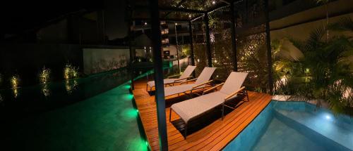 a group of lounge chairs by a swimming pool at night at Vert House in João Pessoa