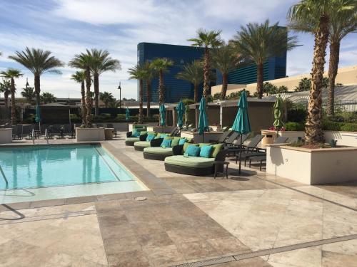 une piscine avec chaises, parasols et palmiers dans l'établissement Luxury Suites International at The Signature, à Las Vegas