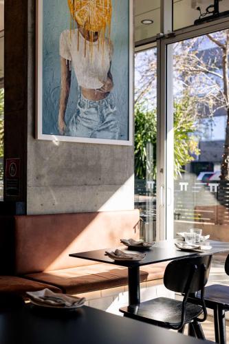 a restaurant with two tables and a picture of a woman at Hotel TOTTO Wollongong in Wollongong