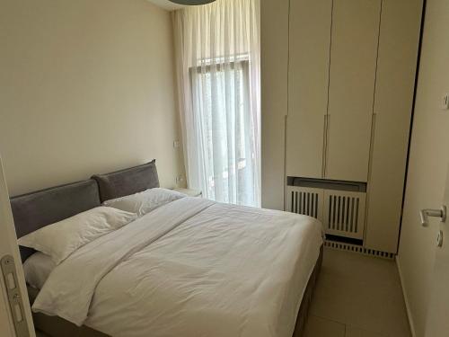 a bedroom with a white bed and a window at Villa Elodie, Green Coast, Palase in Palasë