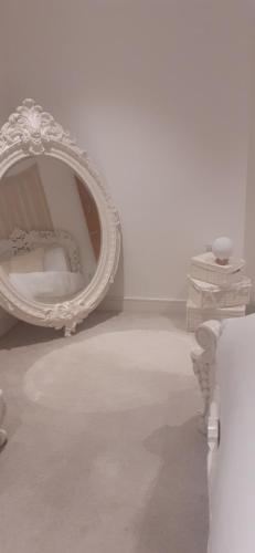 - un miroir blanc dans une pièce blanche avec une chaise dans l'établissement Charming & Cosy Double Room with Balcony in Wembley - Walking Distance to Wembley Stadium!, à Londres