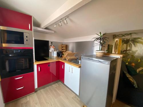 La cuisine est équipée de placards rouges et blancs et d'un réfrigérateur. dans l'établissement La Casa Jungle, à Frontignan