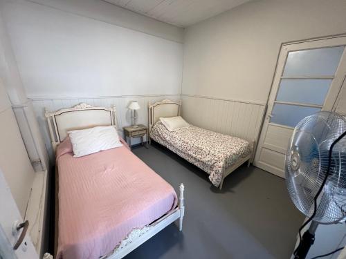 查斯科穆斯Casa a dos cuadras de la laguna的小房间设有两张床和风扇