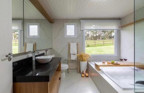 a bathroom with a large tub and a sink at Chalé Top Condado Urubici, banheira e piscina aquecida in Urubici