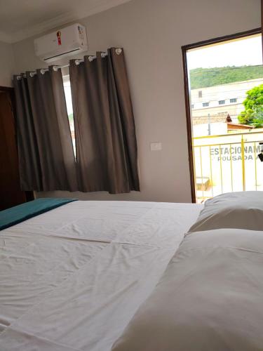 a bedroom with a white bed and a window at Pousada Aliança in Pirenópolis