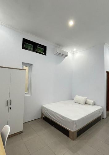 a white bedroom with a bed and a window at Aero Guest House in Timuran