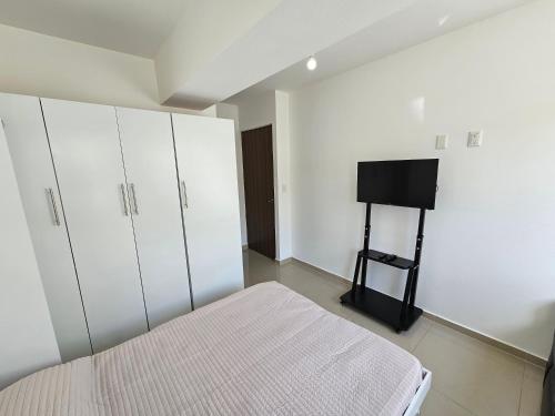 a bedroom with white cabinets and a bed and a television at Habitación con baño privado en departamento compartido cerca de zona de conciertos in Mexico City