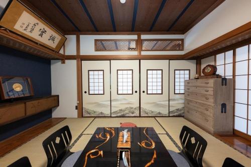a room with a table and chairs and windows at 箱根寄月庵 in Hakone