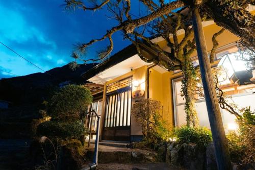 a yellow house with a tree in front of it at 箱根寄月庵 in Hakone