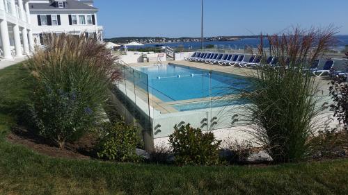 a swimming pool with chairs next to a house at Ocean House Hotel at Bass Rocks in Gloucester