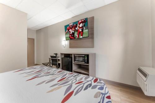 a bedroom with a bed and a tv on a wall at Red Roof Inn Johnstown in Johnstown