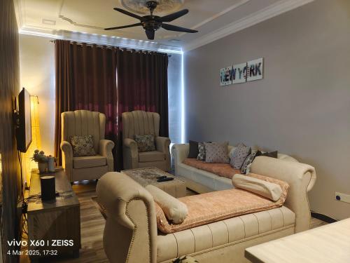 a living room with couches and chairs and a ceiling fan at Penginapan Puncak 28 in Kuala Terengganu