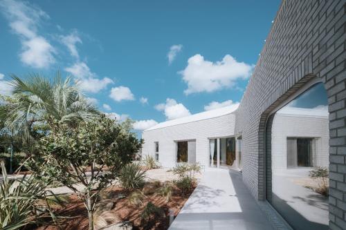 an external view of a white house with a brick wall at Better than good in Jeju