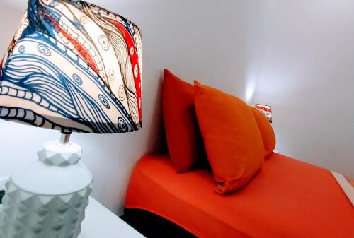 a bed with orange pillows and a lamp on it at Casajungla Hostel in Jacó