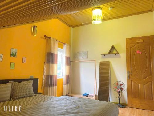 a bedroom with yellow walls and a bed and a window at Happy Dream House - Trung tâm Đà Lạt in Khu Chi Lăng