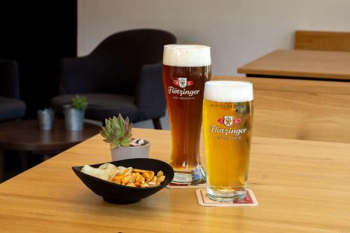 two glasses of beer and a bowl of food on a table at Best Western Hotel Kiefersfelden in Kiefersfelden