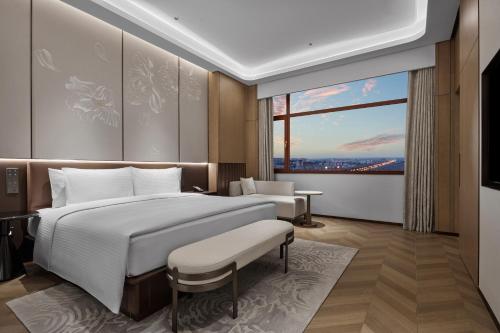 a bedroom with a large bed and a large window at Wanda Jin Hotel Ordos in Ordos