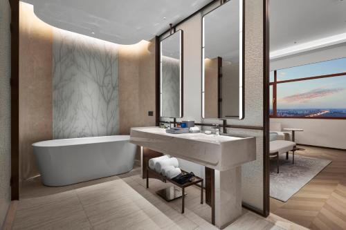 a bathroom with a tub and a sink and a bath tub at Wanda Jin Hotel Ordos in Ordos