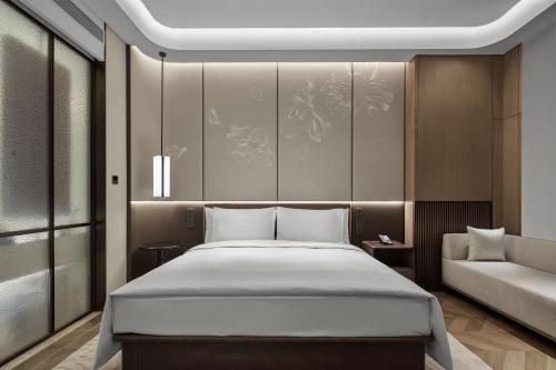 a bedroom with a large bed and a couch at Wanda Jin Hotel Ordos in Ordos