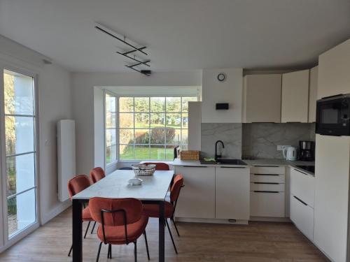 une cuisine avec une table et des chaises et une cuisine avec des armoires blanches dans l'établissement Maison familiale 3 chambres proche plage et golf à Fort-Mahon-Plage - FR-1-482-95, à Fort-Mahon-Plage