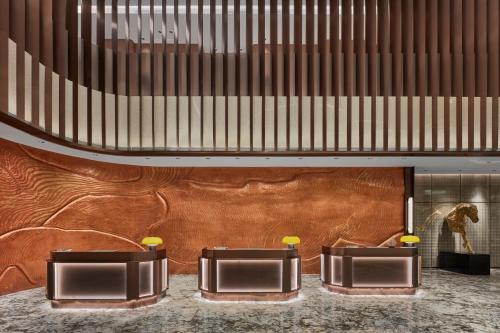 a lobby with two tables and a brown wall at Wanda Jin Hotel Ordos in Ordos