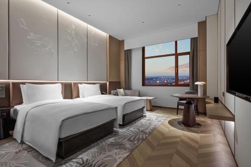 a hotel room with two beds and a television at Wanda Jin Hotel Ordos in Ordos