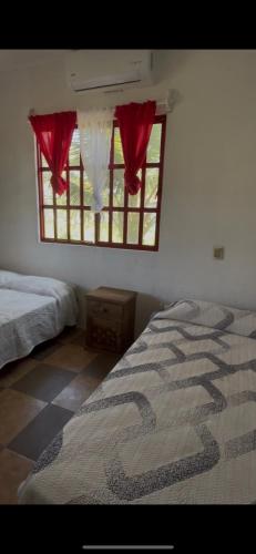 a bedroom with two beds and a window with red curtains at Quinta Raquel in Monte Gordo