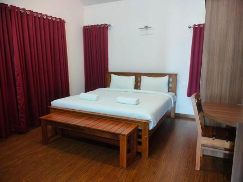 a bedroom with a bed with red curtains and a bench at Blissfull Meadows in Ooty