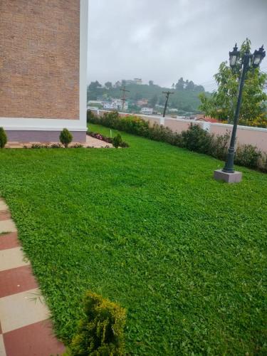 a green lawn with a street light next to a building at Blissfull Meadows in Ooty