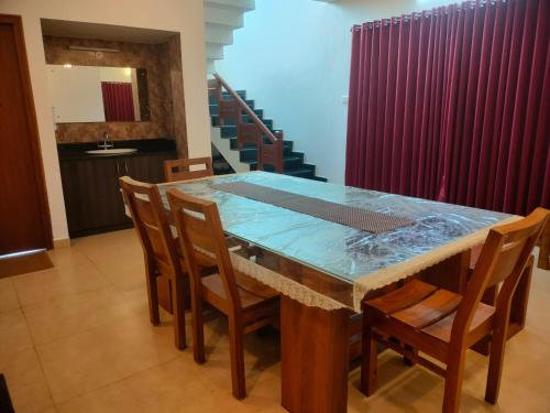 a dining room table with a glass top and chairs at Blissfull Meadows in Ooty