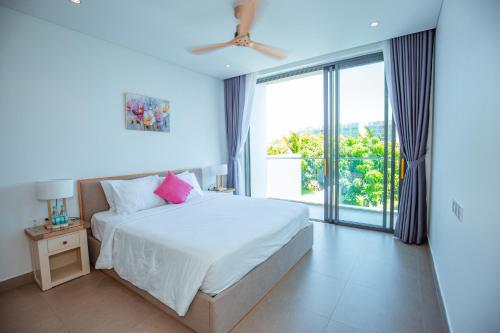 a bedroom with a white bed and a large window at Sanctuary Villa Ho Tram in Ho Tram