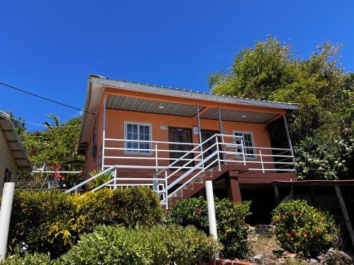 an orange house with white railings and trees at POSADA BLUE WAVE VIEW in Archibolds