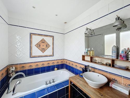 La salle de bains bleue et blanche est pourvue d'une baignoire et d'un lavabo. dans l'établissement Maison 10 pers, proche mer, terrasse, 2 parkings - FR-1-475-219, à Saintes-Maries-de-la-Mer