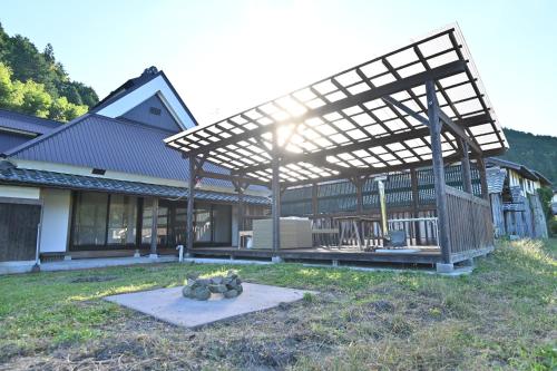 a wooden pergola on a house in a yard at 古民家ゲストハウスSatoyama in Kokuryō