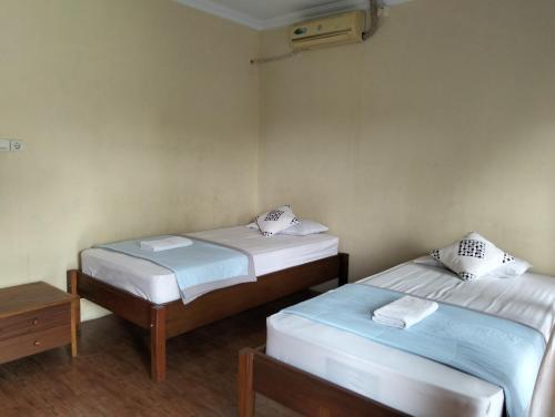 two twin beds in a room with a table at Opak Village Bed & Breakfast in Bantul