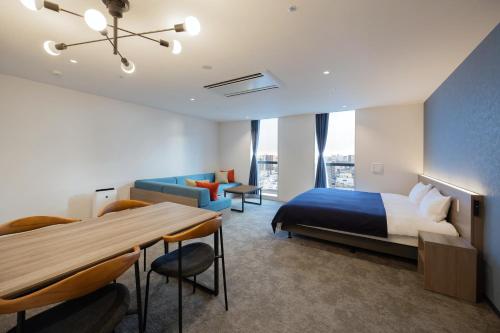 a hotel room with a bed and a table and chairs at Minn STATION Ai Nagoya in Aoichō