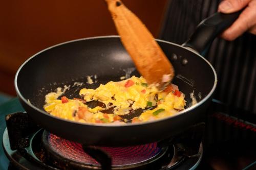 a person cooking food in a pan on a stove at Ariston Hotel Bangkok in Bangkok