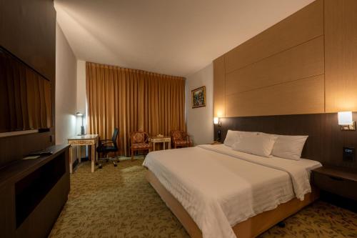 a hotel room with a bed and a desk at Ariston Hotel Bangkok in Bangkok